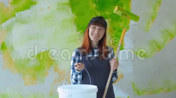 一个年轻女孩做修理那个拿着滚筒的女孩在墙上画画女孩修理和微笑绘画视频的预览图