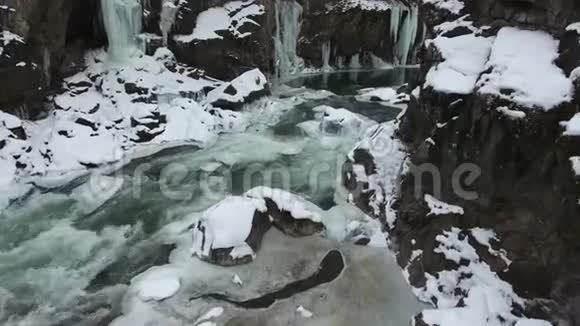 飞越峡谷底部的冬季河流冰柱挂在峡谷的石壁上视频的预览图