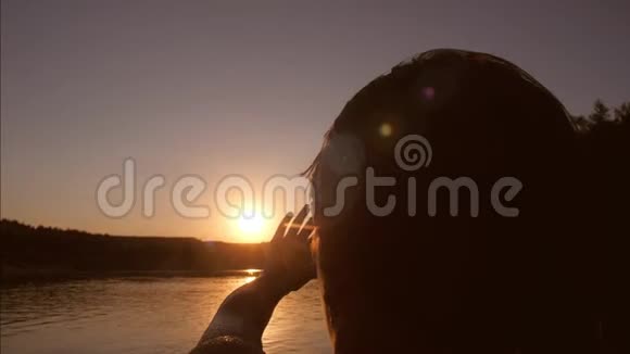 女孩站在河里把手伸向太阳日落在河上抚摸孩子他的手照太阳视频的预览图