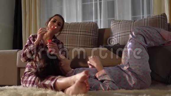 在舒适的客厅里两对成年双胞胎穿着漂亮的睡衣玩着泡泡视频的预览图