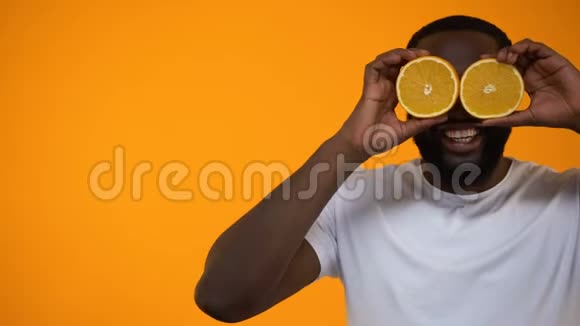 微笑的非裔美国人把一半的橘子放在眼睛上素食的生活方式视频的预览图