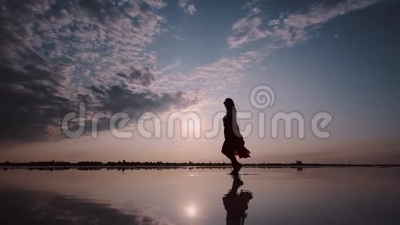 一个女人在夕阳背景下挥舞着裙子的剪影视频的预览图