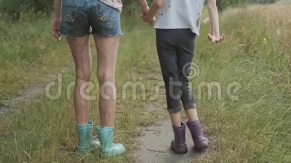 两个快乐的女孩姐妹在雨后穿着脏衣服牵着手散步视频的预览图
