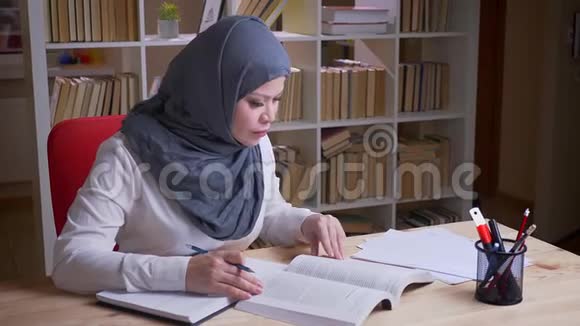 穆斯林成年女学生戴头巾参加医学考试阅读一本书并做笔记视频的预览图