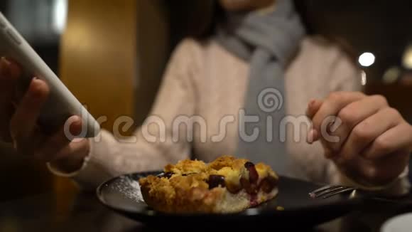 女士坐在咖啡馆里喝着带馅饼的咖啡用手机关门视频的预览图