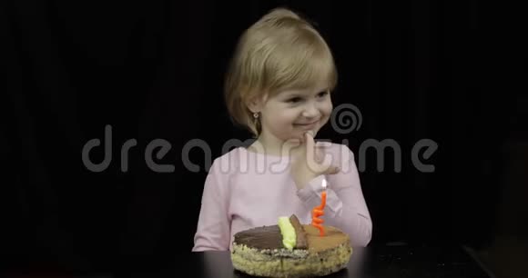 小可爱的女孩在黑色背景的生日蛋糕上吹上节日的蜡烛视频的预览图