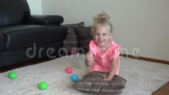 穿粉色连衣裙的漂亮女孩用双手在家里地板上打枕头视频的预览图