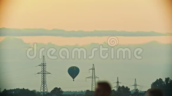 一个蓝黄相间的气球飞过田野通讯塔天线塔晚上视频的预览图