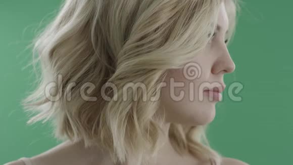 性感的年轻女人把脸转向相机对着绿色的屏幕微笑视频的预览图