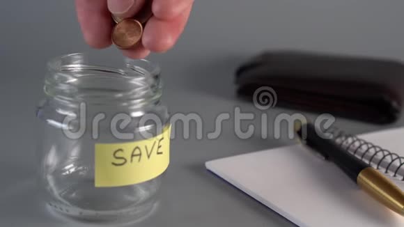 一只手正在往一个玻璃罐里扔硬币硬币和欧元上面写着SAE视频的预览图