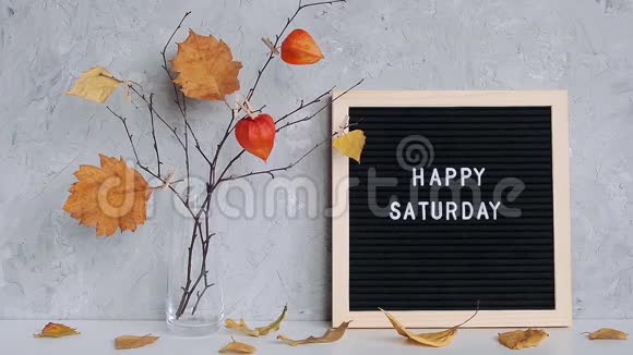 周六快乐的短信在黑色的信纸板和花枝黄叶在花瓶在桌上视频的预览图