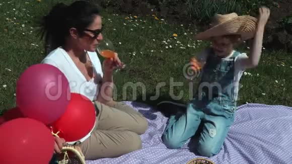 快乐的母女在户外野餐时喝果汁或柠檬水视频的预览图