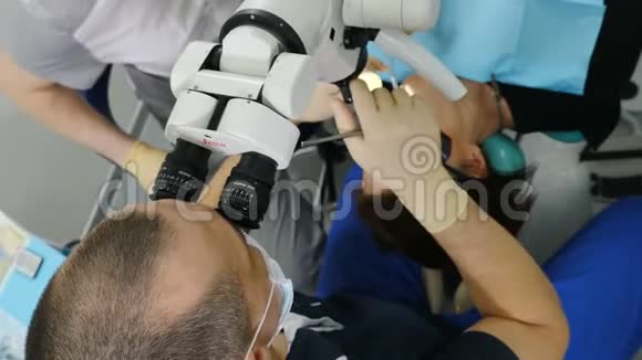 使用显微镜对医生的俯视图现代牙科诊所的牙医治疗病人正畸医生与一名视频的预览图