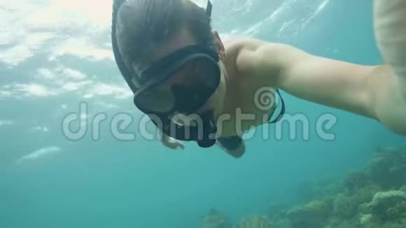 年轻人带着浮潜和面具在海上浮潜拍摄自拍视频在珊瑚礁和海底游泳的人视频的预览图