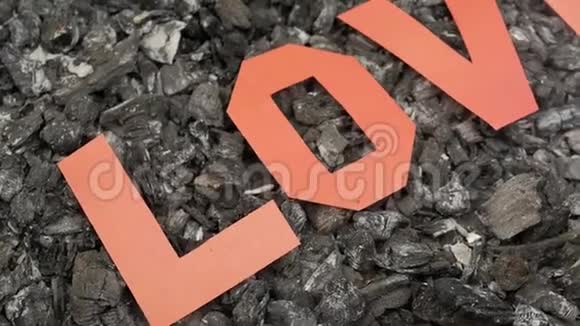 在炎热的烟煤上铭文的爱是由纸上剪下的字母制成的视频的预览图
