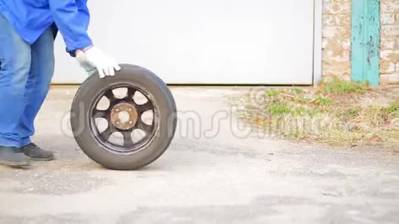 一个人在沥青上用圆盘滚动汽车轮胎视频的预览图