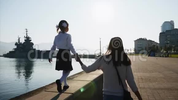 一个穿校服的女孩正和妈妈一起走在长廊的栏杆上视频的预览图