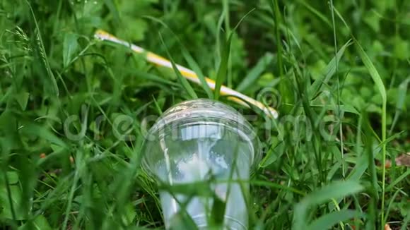 女人手把塑料杯从草地上移开把塑料杯移开视频的预览图