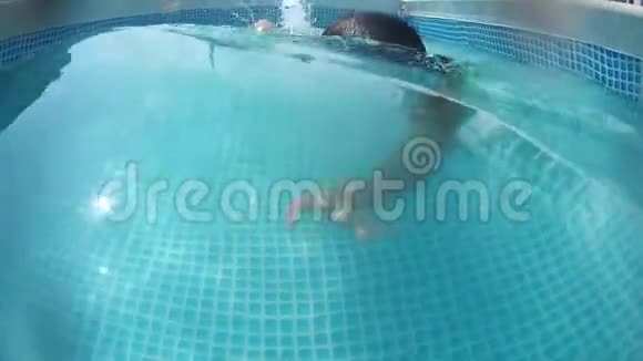 快乐的小男孩在游泳池里水下潜水一次水下射击视频的预览图