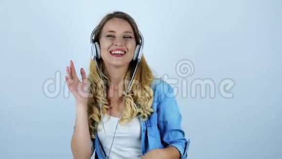 年轻漂亮性感的金发女郎戴着耳机跳舞在孤独的白色背景下感到快乐视频的预览图
