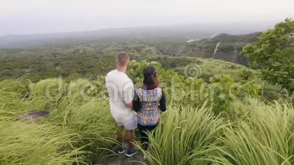 幸福夫妇拥抱在青山上欣赏美丽的风景男人和女人拥抱在青山上视频的预览图