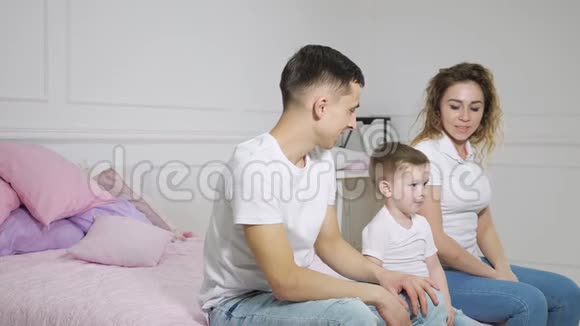 年轻的家庭男人女人和男孩正在床上摔倒动作缓慢视频的预览图