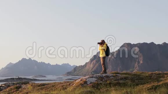 一位女士用数码单反相机从山上拍摄挪威风景视频的预览图