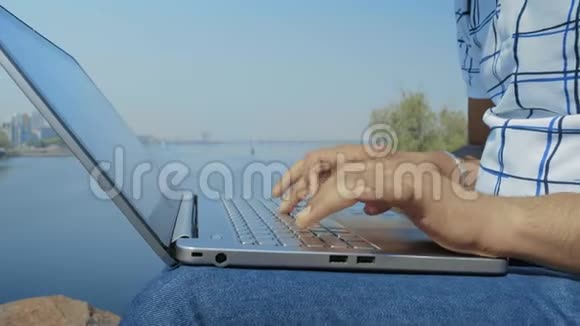 河岸笔记本电脑键盘上的印度学生手类型文本特写视频的预览图