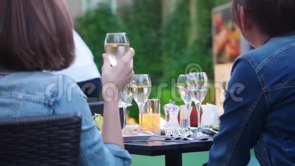 两个女人坐在桌子旁边看着舞台上的表演喝酒和吃饭户外视频的预览图