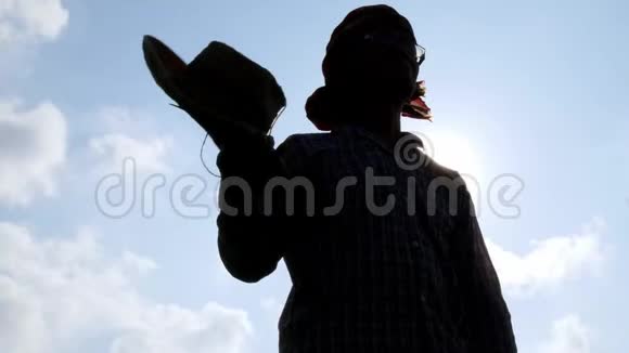 在天空背景下一位亚洲老农下班后摘下帽子擦去脸上的汗水视频的预览图