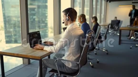 商务人士在办公室工作时使用笔记本电脑的耳机后视视频的预览图
