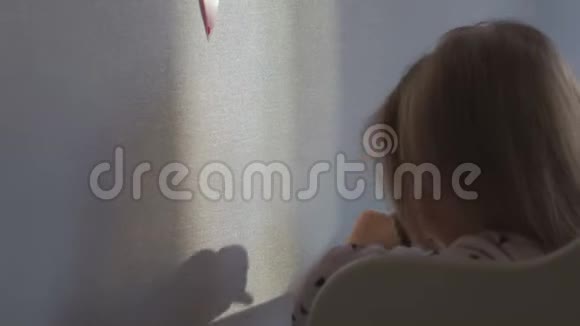 一个在婴儿床上醒来的小女孩在墙上玩一个影子视频的预览图