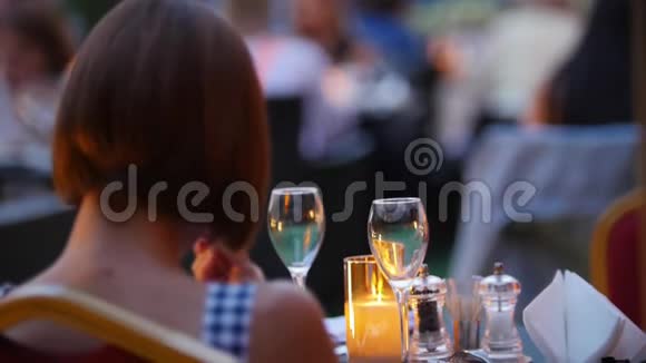 一位坐在桌子旁的女人在菜单上翻来覆去户外餐馆傍晚时分视频的预览图