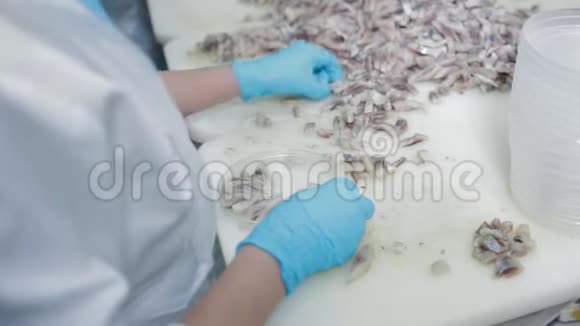 女工戴着防护手套把鱼蜜饯倒入塑料罐子里鱼类蜜饯生产鱼类分类视频的预览图