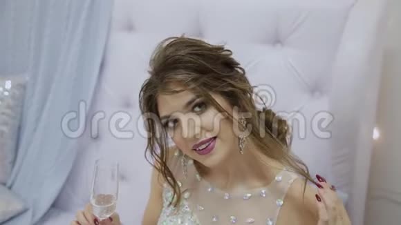 非常漂亮的女孩喝香槟坐在沙发上新年装饰视频的预览图