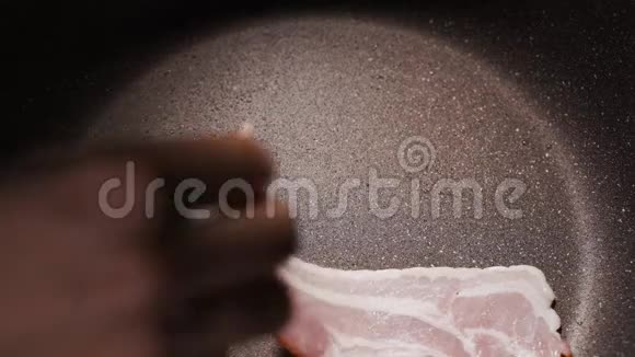 一个女人正在煎锅里煮咸肉带烟和煎油的美味食物视频的预览图