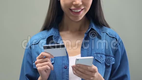 亚洲女士持有智能手机和信用卡网上银行服务购物视频的预览图