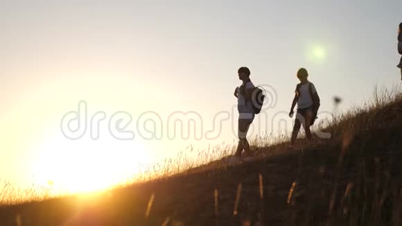 一家带着孩子在日落时旅行的游客带着背包的孩子和妈妈乘着一缕缕阳光在山上旅行视频的预览图