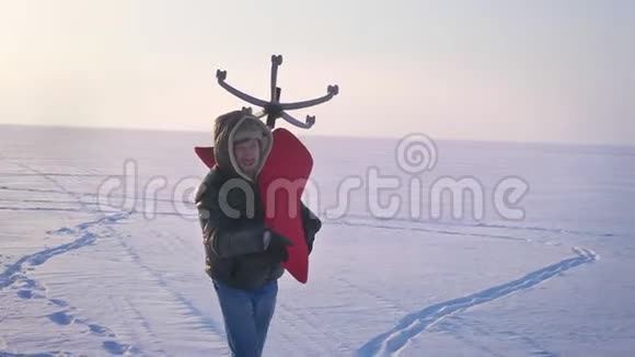 多莉在雪地背景上穿着暖和的外套戴着兜帽的男人的侧脸上高兴地射了一把红色的椅子视频的预览图