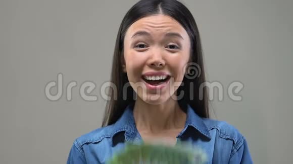 兴奋的亚洲女士向镜头展示了一堆欧元彩票中奖者财富视频的预览图