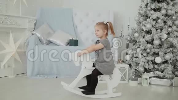 非常漂亮的小女孩骑着一匹木马在新年房间里微笑视频的预览图