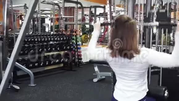 年轻漂亮的运动女性在健身房的下拉杆锻炼机上进行背部肌肉锻炼视频的预览图
