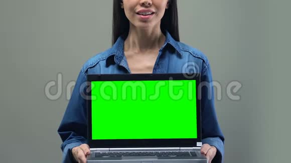 微笑的女人拿着绿色屏幕的笔记本电脑IT应用程序开发视频的预览图