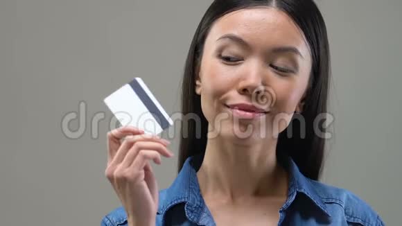 美丽的亚洲女人看着信用卡想着花钱视频的预览图