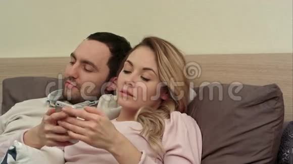 妻子和丈夫看有趣的电影讨论女人用智能手机视频的预览图