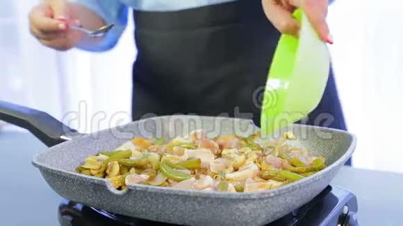 一个女人在平底锅里把木铲和鸡片和豆子蘑菇和酱油混合在一起时间跨度视频的预览图