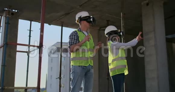 整理肖像两名现代建筑工人使用VR设备可视化现场项目复制空间视频的预览图