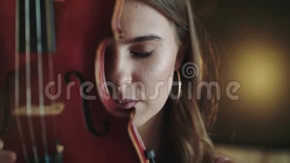 神秘而热情地看着脸上拿着小提琴的女孩的镜头视频的预览图