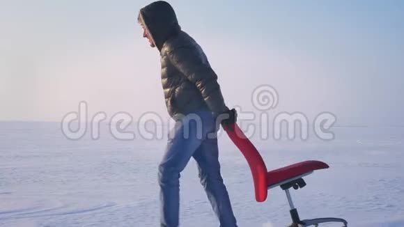 多利宽的运动员穿着温暖的外套和引擎盖慢慢地拉着一把红色的椅子沿着雪场视频的预览图