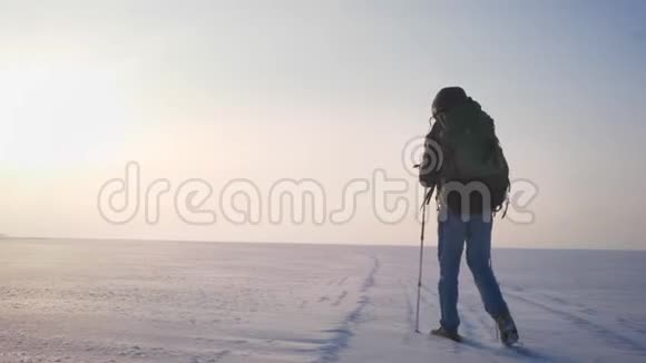 后肖像男背包手拿着山棍和巨大的袋子沿着雪域慢慢地走着视频的预览图
